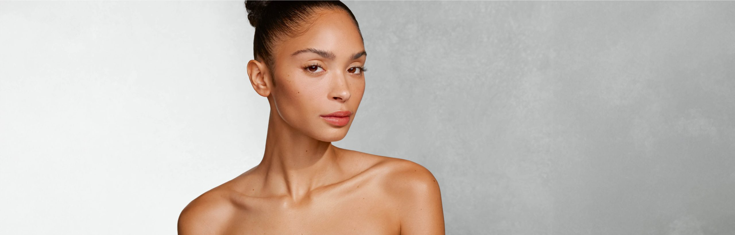 Frau mit hochgestecktem Haar und nackten Schultern blickt leicht gedreht